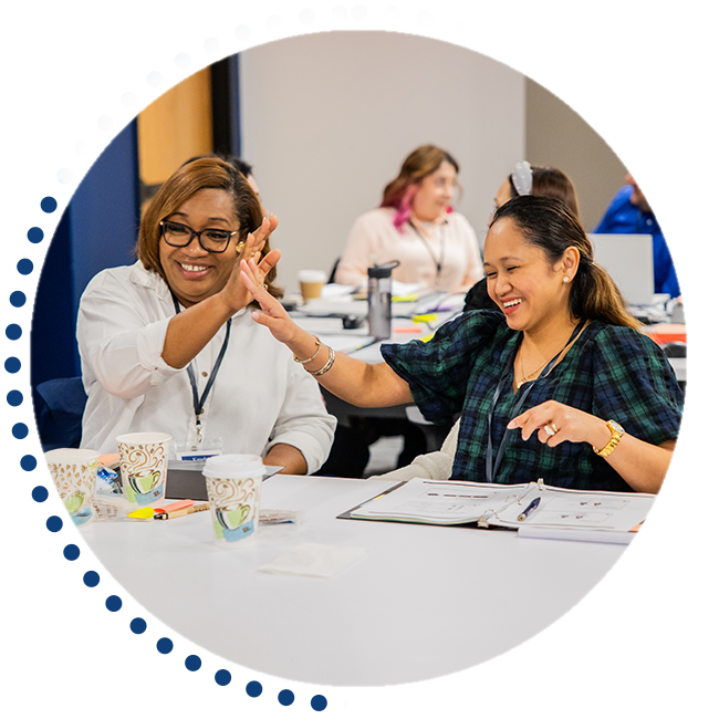 Two people laughing and giving a high five in a conference room